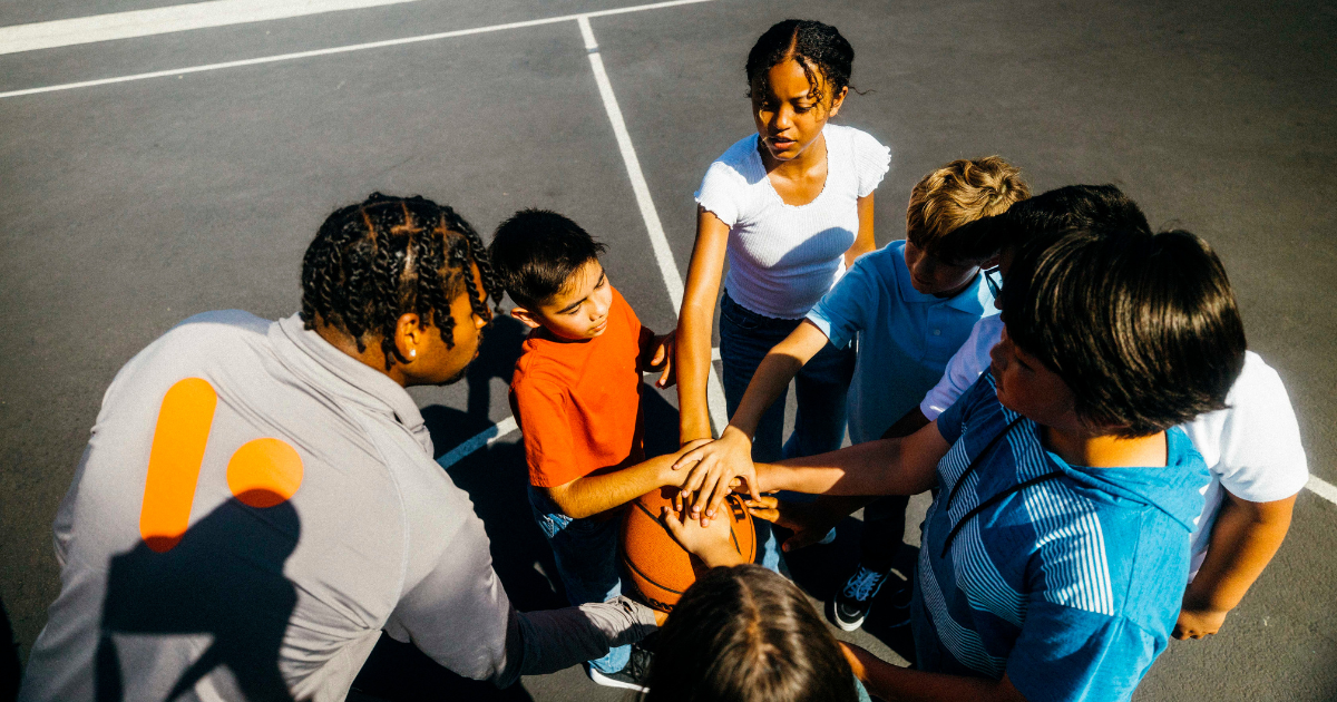 Basketball team and coach with hands all in a circle in a team agreement.